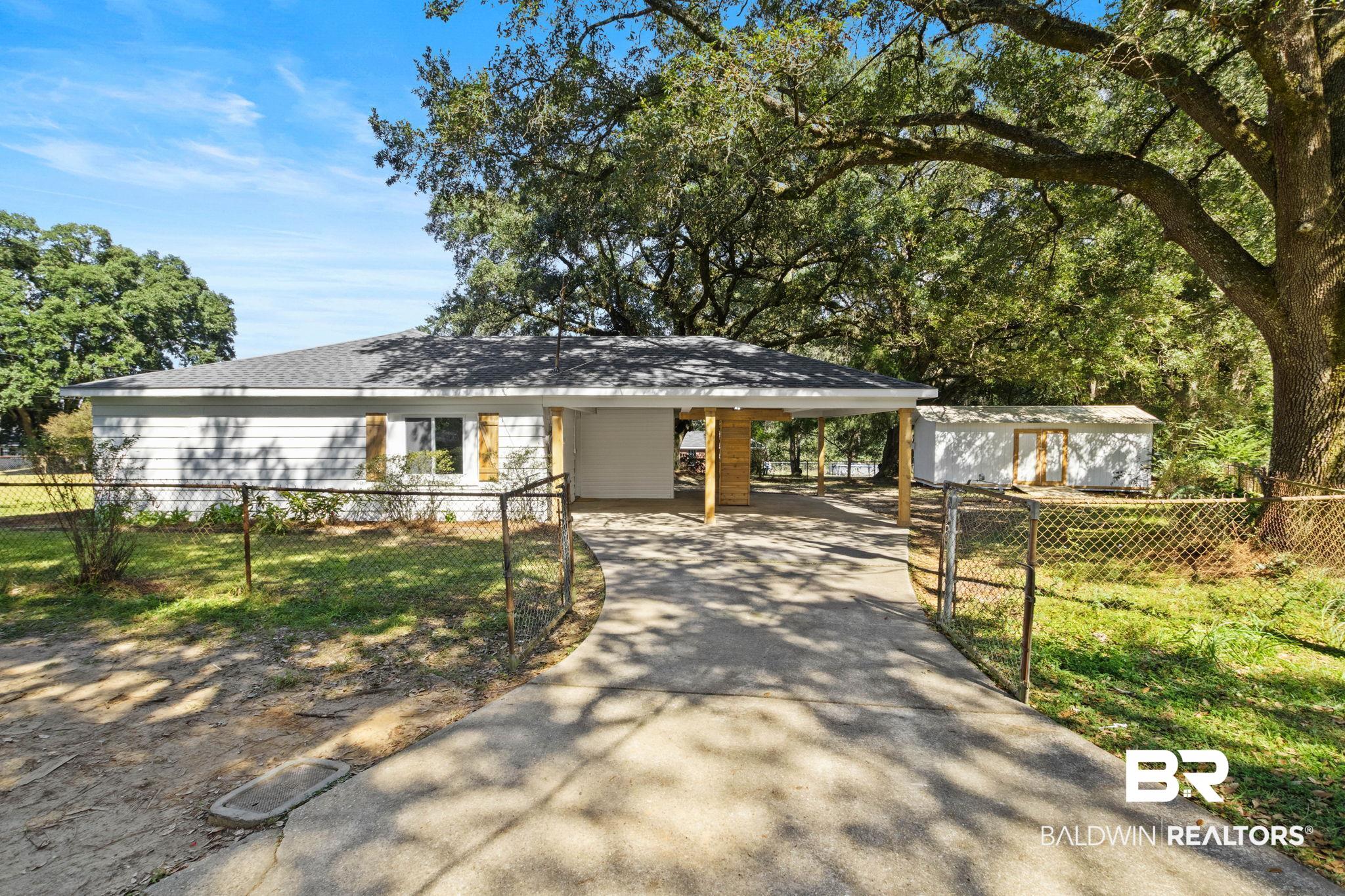 618 Pine Street Saraland, AL 36571 - Photo 4 of 41 View of front of property featuring a fenced front yard, an attached carport, concrete driveway, and roof with shingles