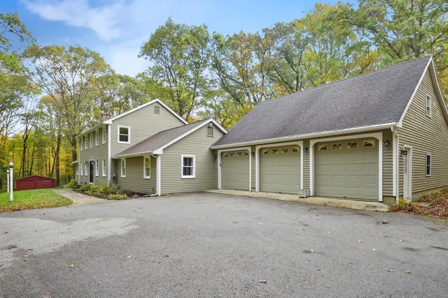 front view of house with a yard and trees all around