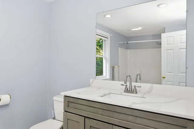 a bathroom with a granite countertop sink a toilet and a mirror