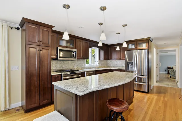 a kitchen with granite countertop a table chairs stainless steel appliances and wooden floor