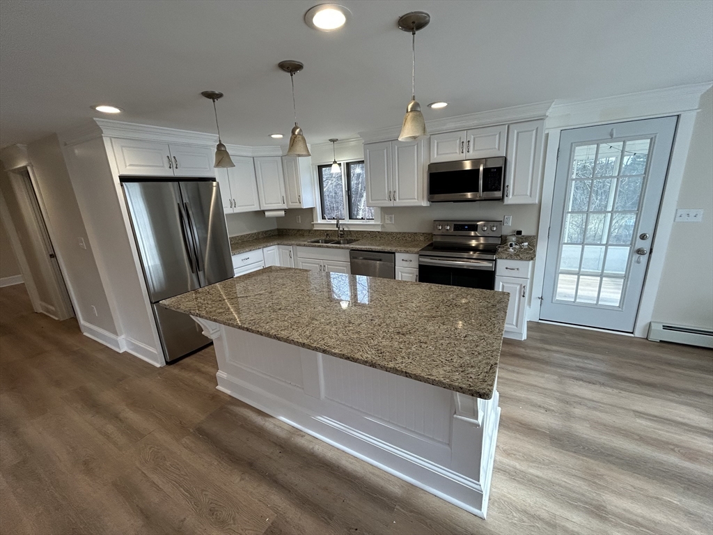 256 Old Webster Road, Unit 1 Oxford, MA 01540 - Photo 4 of 19 a kitchen with stainless steel appliances granite countertop a refrigerator a stove top oven a sink and dishwasher