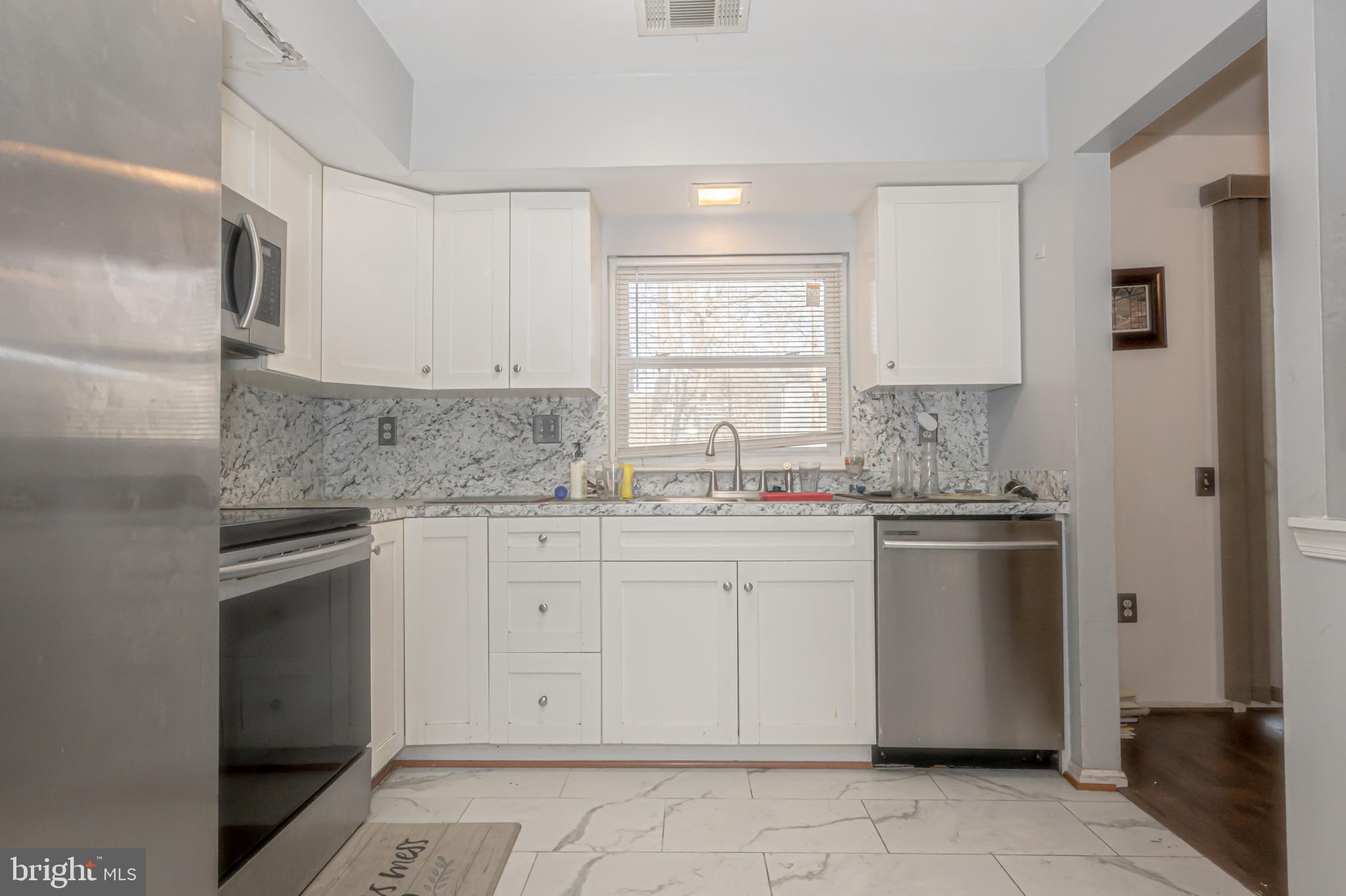 2637 Rooks Head Place Waldorf, MD 20602 - Photo 3 of 18 a kitchen with granite countertop white cabinets stainless steel appliances a sink and a window