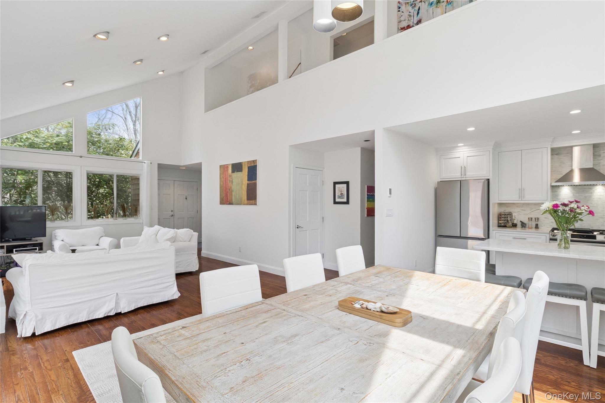Dining space with dark wood-style floors, recessed lighting, baseboards, and a towering ceiling