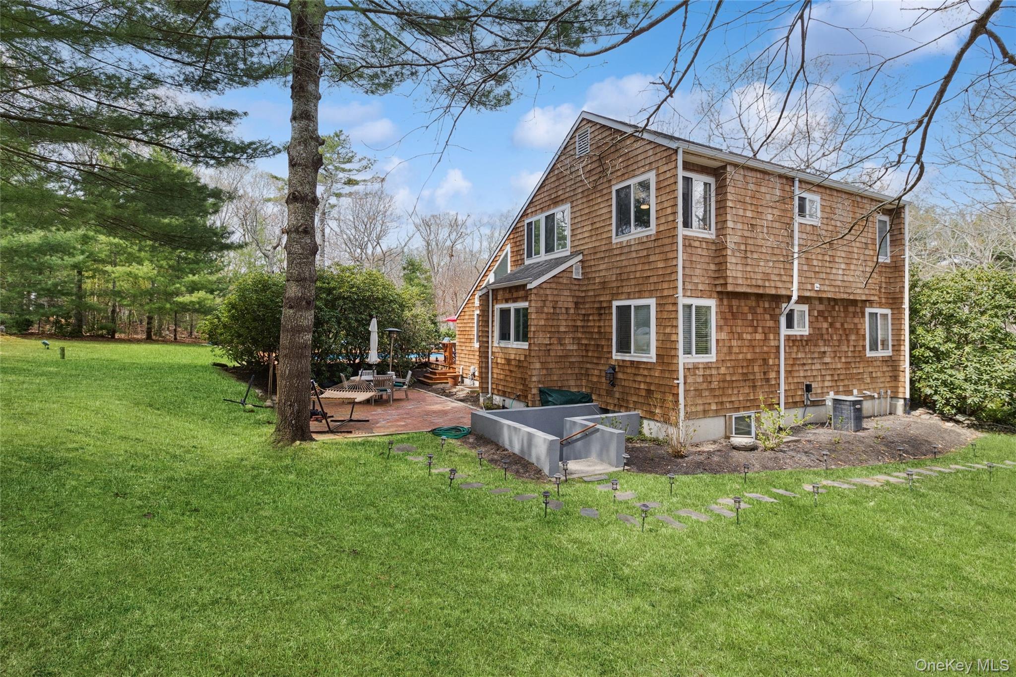 27 Ely Brook Road East Hampton, NY 11937 - Photo 19 of 50 Rear view of property featuring a lawn, a patio area, and central AC