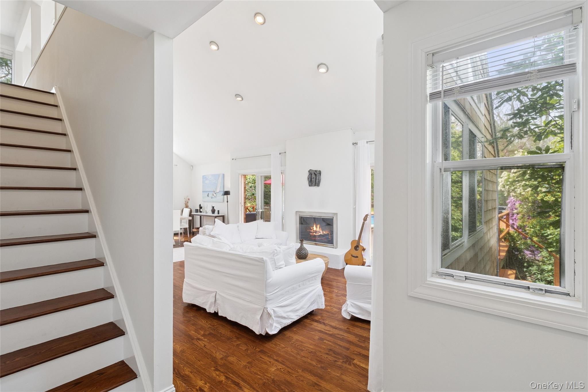 27 Ely Brook Road East Hampton, NY 11937 - Photo 41 of 50 Living area with stairway, a healthy amount of sunlight, a glass covered fireplace, and dark wood-style flooring