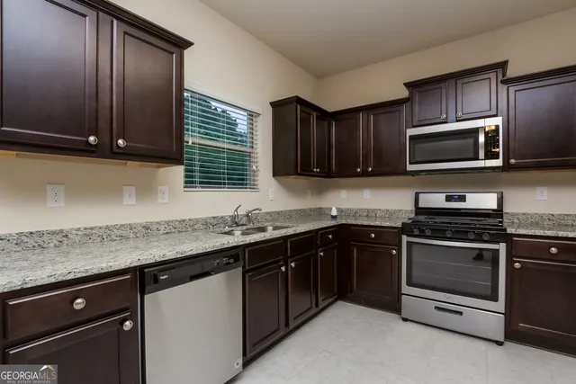a kitchen with stainless steel appliances granite countertop wooden cabinets and a stove top oven