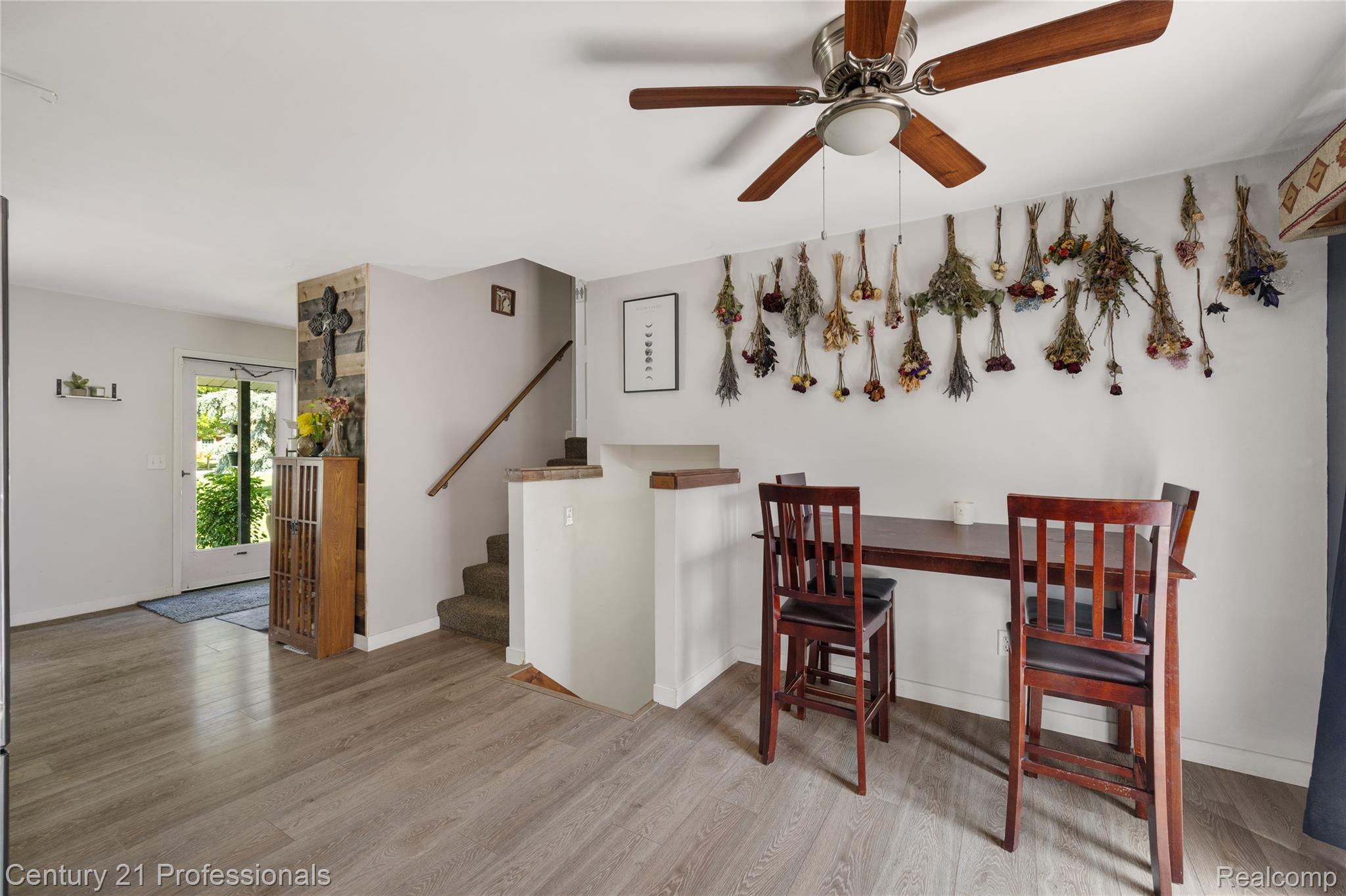 15037 Hogan Road Linden, MI 48451 - Photo 8 of 38 Open-concept living area featuring wood-finish flooring, a ceiling fan with integrated lighting, and a staircase with a wooden handrail