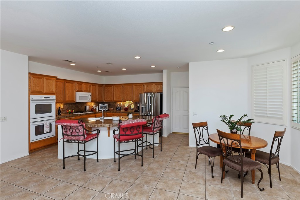 11416 Bridgeway Drive Riverside, CA 92505 - Photo 14 of 54 a kitchen with stainless steel appliances a dining table chairs and granite counter tops