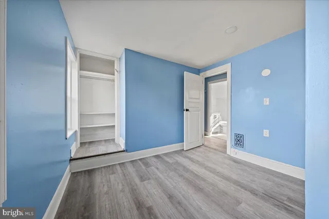 a view of an empty room with wooden floor and closet