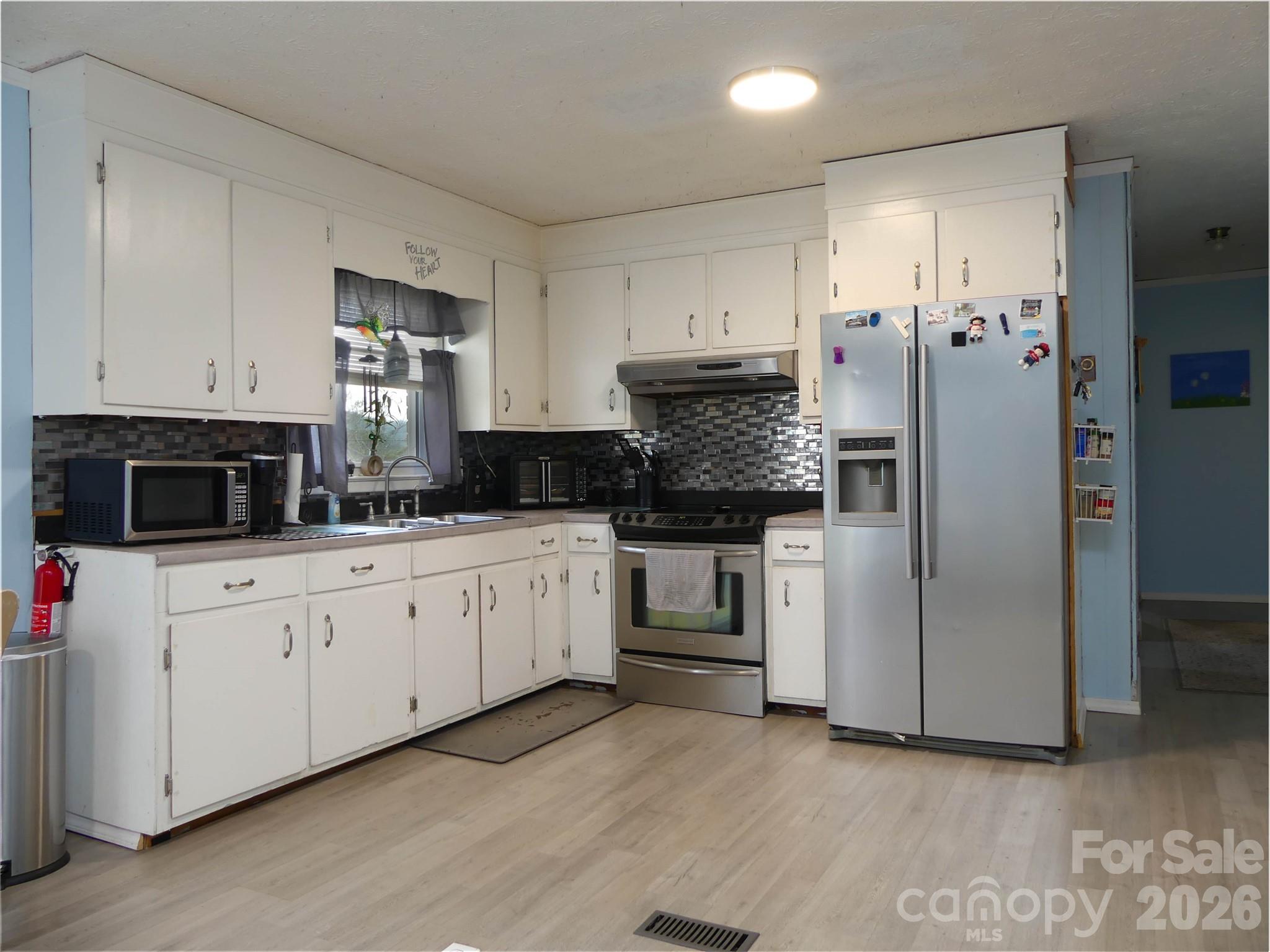 4636 Oak Hill School Road Lenoir, NC 28645 - Photo 10 of 23 a kitchen with white cabinets and stainless steel appliances