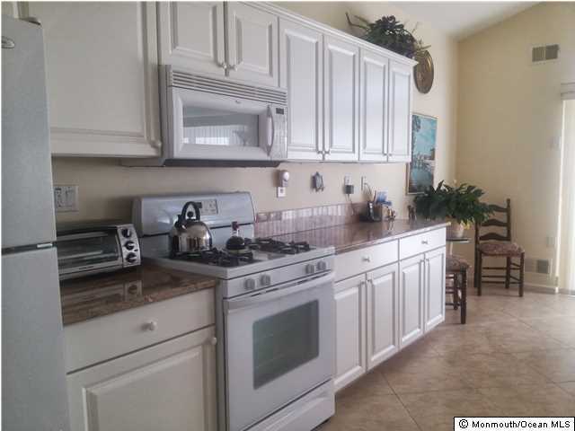 21 Lorenzo Road Manchester Township, NJ 08759 - Photo 4 of 17 a kitchen with granite countertop white cabinets and white appliances