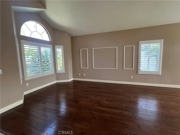 an empty room with wooden floor windows and cabinet