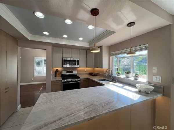 a kitchen with kitchen island a large counter top space a sink stainless steel appliances and windows