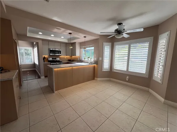 a kitchen with stainless steel appliances granite countertop a stove top oven a sink a dining table and chairs