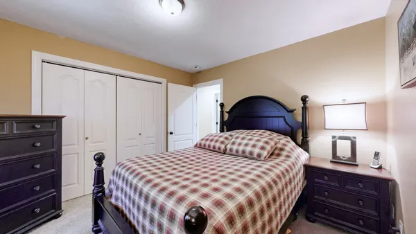 a bedroom with a bed and a lamp on dresser