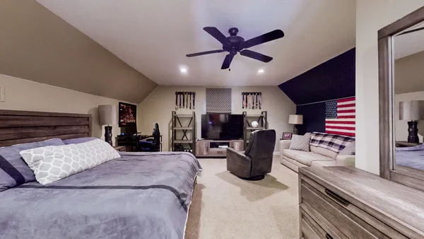 a spacious bedroom with a bed a couch and a chandelier