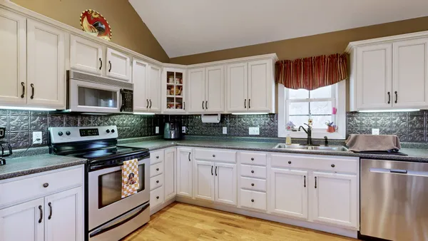 a kitchen with granite countertop a stove a sink dishwasher and white cabinets with wooden floor