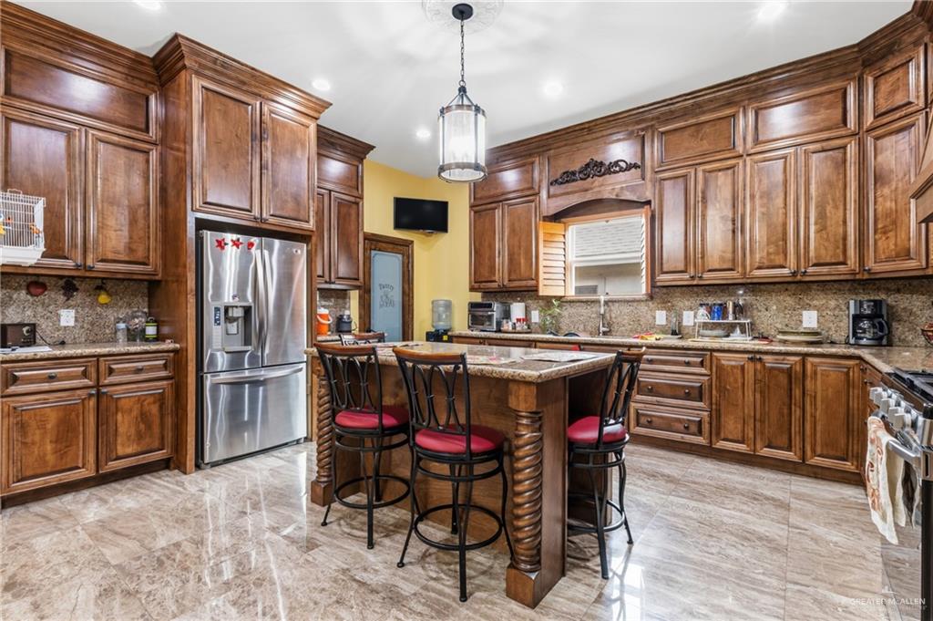 717 West 27th Street Mission, TX 78574 - Photo 3 of 18 a kitchen with stainless steel appliances granite countertop a refrigerator a sink dishwasher a stove and white cabinets with wooden floor