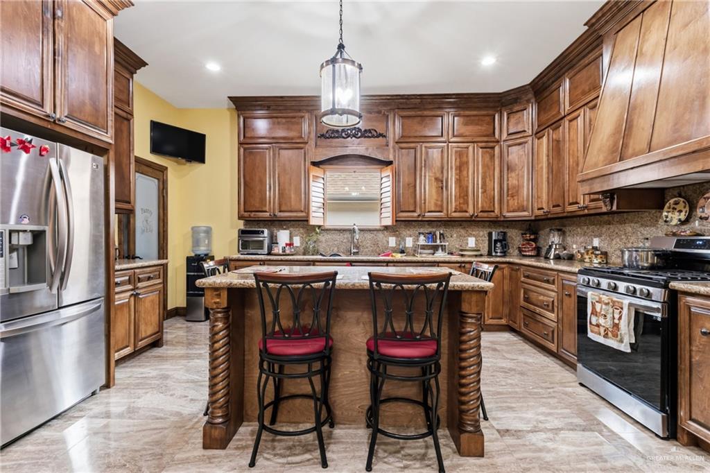 717 West 27th Street Mission, TX 78574 - Photo 4 of 18 a kitchen with stainless steel appliances granite countertop a stove top oven a refrigerator a sink and chairs