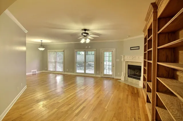 a view of an empty room with a fireplace and wooden floor