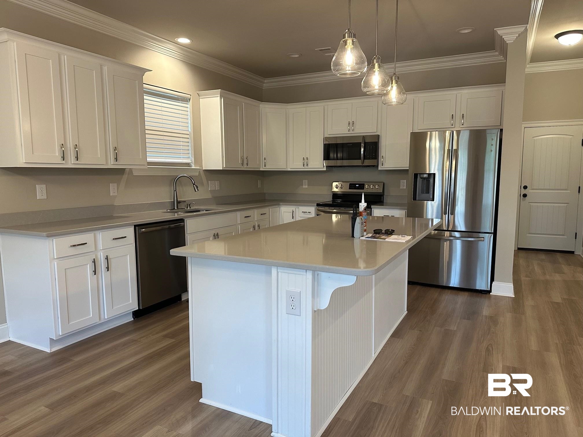 1009 Ruisseau Drive Foley, AL 36535 - Photo 23 of 55 Kitchen with sink, a center island, stainless steel appliances, and white cabinetry