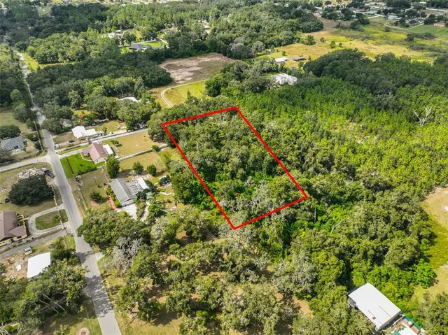 an aerial view of residential house with outdoor space and trees all around