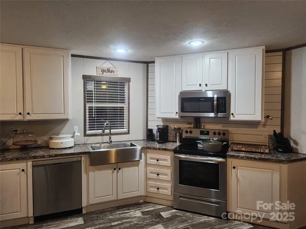 a kitchen with stainless steel appliances granite countertop a stove a sink and a microwave