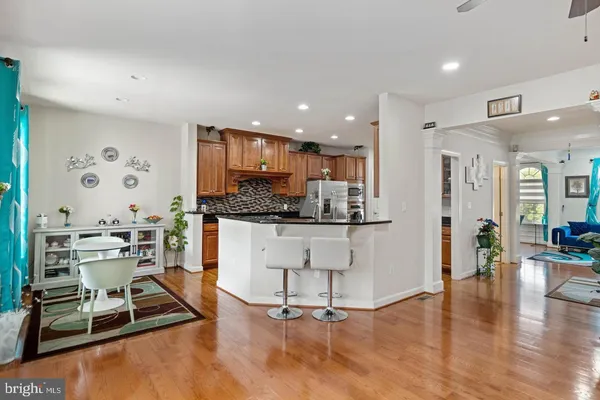 a kitchen with stainless steel appliances kitchen island granite countertop a stove a refrigerator and white cabinets with wooden floor