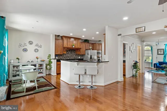 a kitchen with stainless steel appliances kitchen island granite countertop a stove a refrigerator and white cabinets with wooden floor