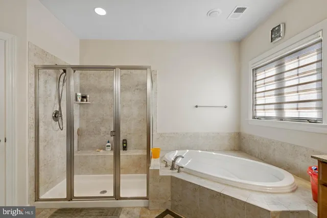 a bathroom with a white bath tub a shower and a sink