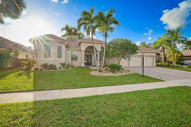 a front view of a house with a yard and palm trees