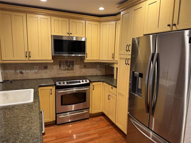 a kitchen with stainless steel appliances granite countertop a refrigerator stove and sink