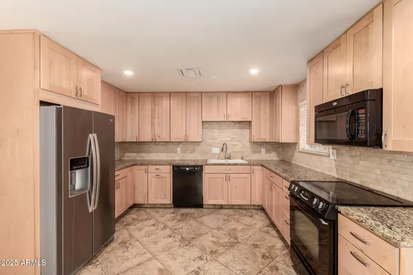 a kitchen with stainless steel appliances granite countertop a refrigerator stove microwave and sink