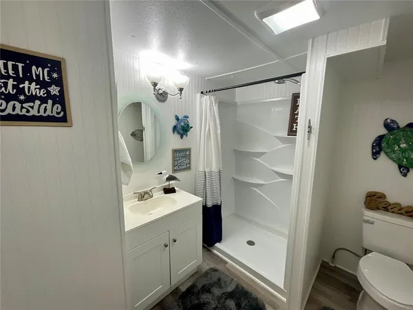a bathroom with a shower sink vanity mirror and toilet