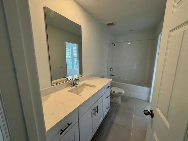a bathroom with a granite countertop sink a toilet and shower