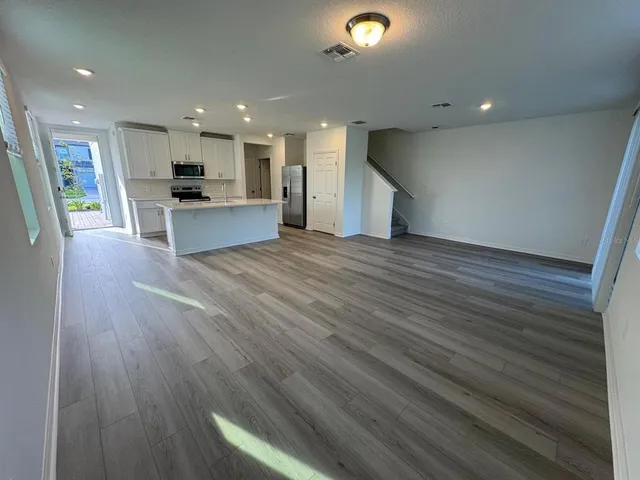 a view of kitchen with kitchen island wooden floor center island and stainless steel appliances