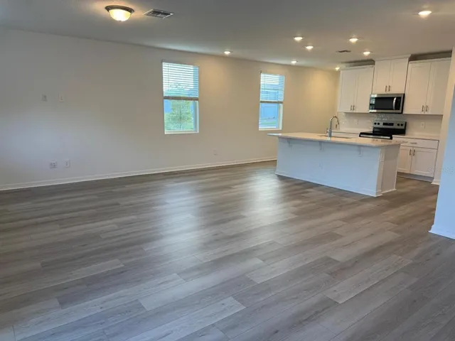 an open kitchen with kitchen island a sink wooden floor and a stove