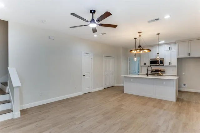 a kitchen with stainless steel appliances kitchen island a refrigerator sink and white cabinets