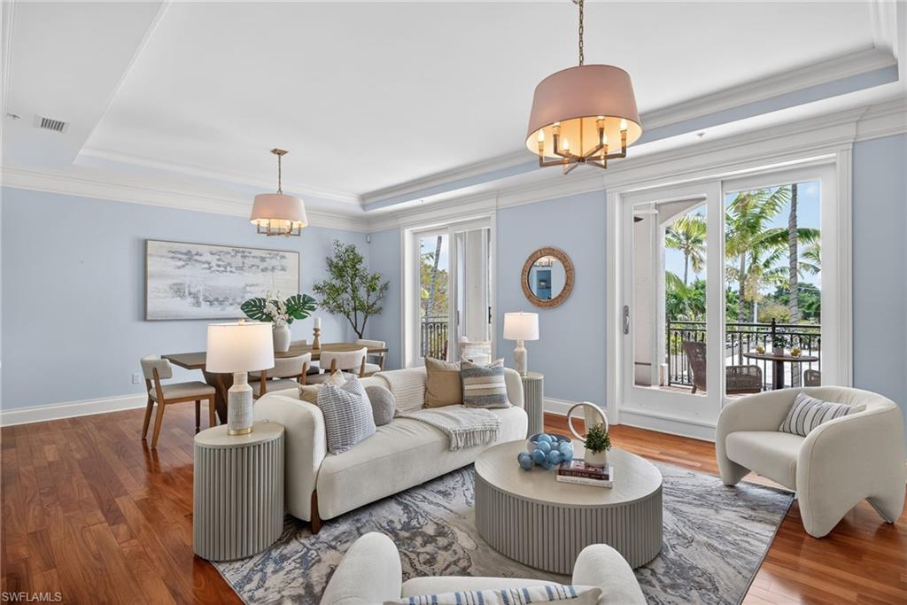 Living area with a tray ceiling, crown molding, wood finished floors, and suspended lighting