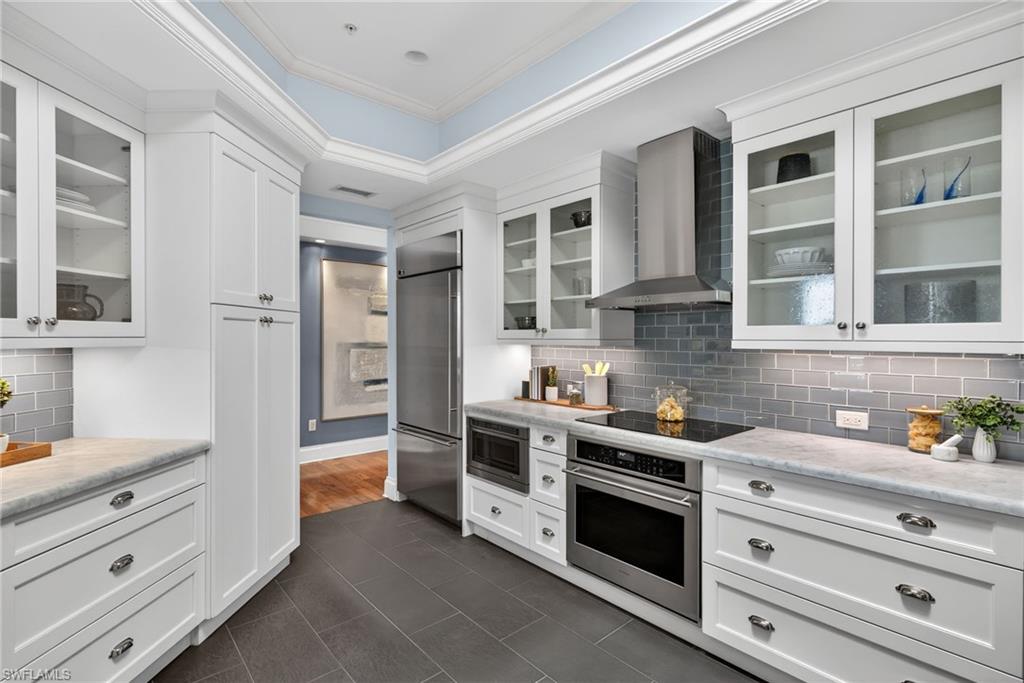 625 5th Avenue South, Unit PH302 Naples, FL 34102 - Photo 12 of 33 Kitchen with glass fronted cabinets, decorative backsplash, built in appliances, white cabinets, and crown molding