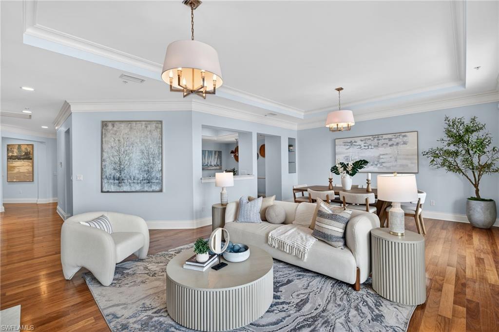 625 5th Avenue South, Unit PH302 Naples, FL 34102 - Photo 2 of 33 Living area featuring wood finished floors, suspended lighting, a tray ceiling, and crown molding