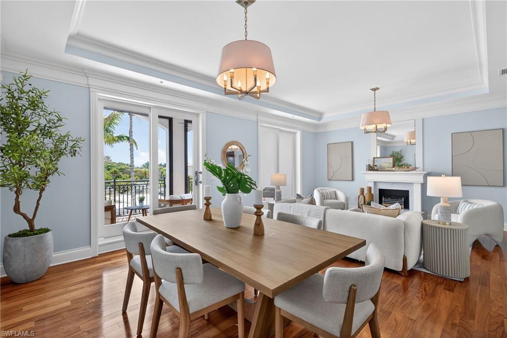 625 5th Avenue South, Unit PH302 Naples, FL 34102 - Photo 5 of 33 Dining area featuring a raised ceiling, a fireplace, wood-type flooring, a chandelier, and crown molding