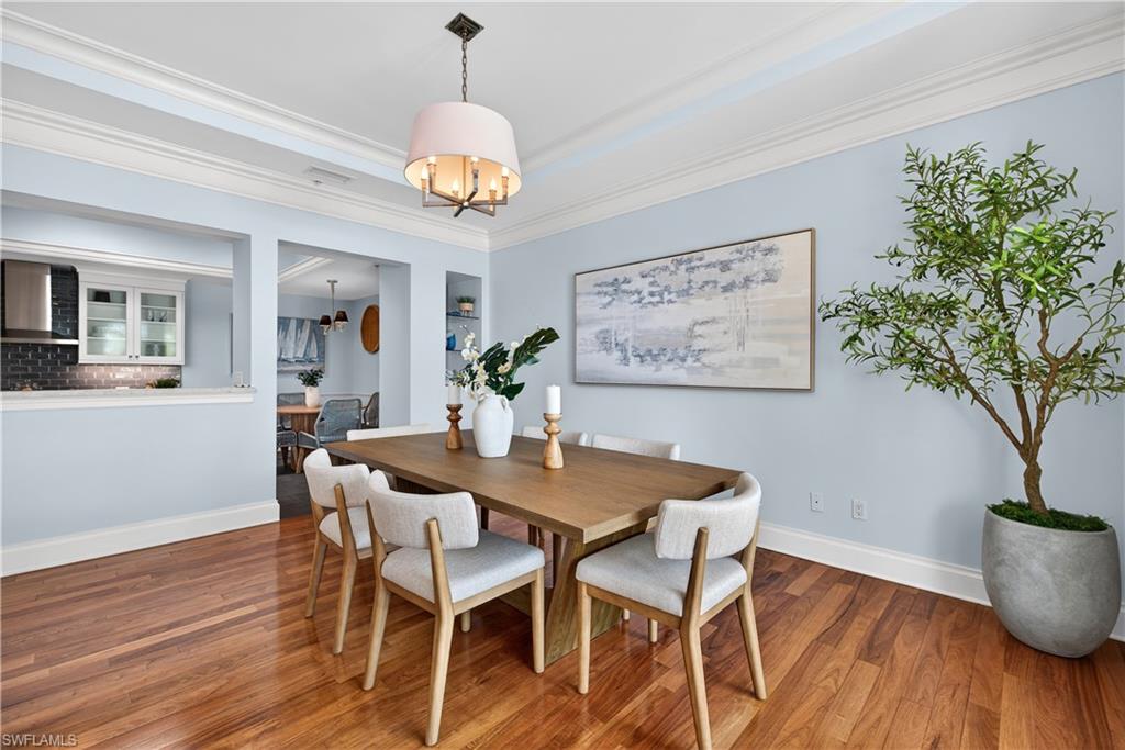 625 5th Avenue South, Unit PH302 Naples, FL 34102 - Photo 7 of 33 Dining area featuring hardwood / wood-style floors, crown molding, a chandelier, and a raised ceiling