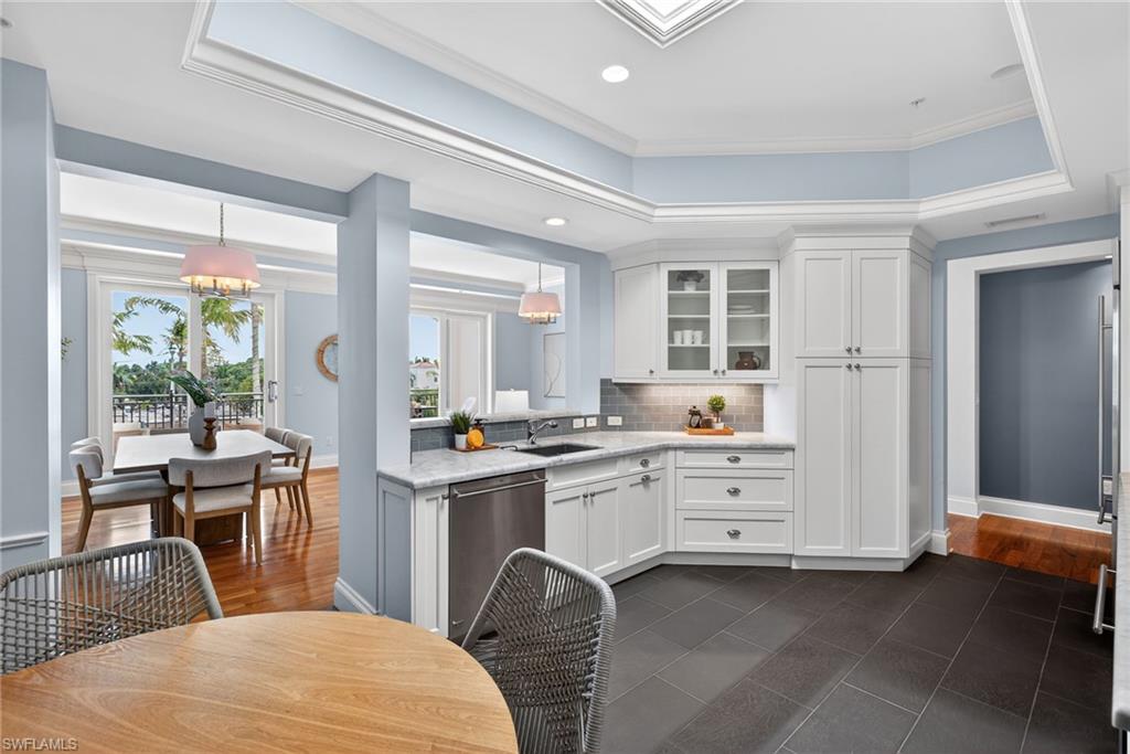 625 5th Avenue South, Unit PH302 Naples, FL 34102 - Photo 8 of 33 Kitchen featuring a raised ceiling, glass insert cabinets, dark tile patterned floors, stainless steel dishwasher, and light stone counters