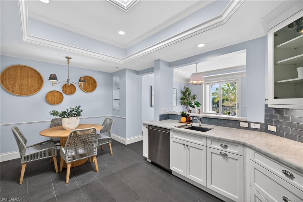 625 5th Avenue South, Unit PH302 Naples, FL 34102 - Photo 9 of 33 Kitchen with a raised ceiling, backsplash, glass insert cabinets, white cabinets, and hanging light fixtures