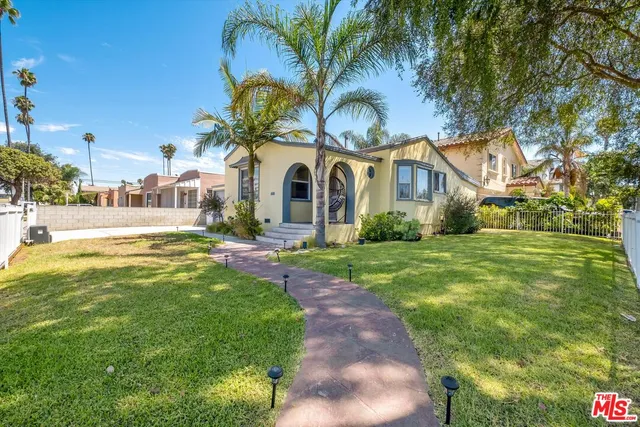 a front view of a house with garden and trees