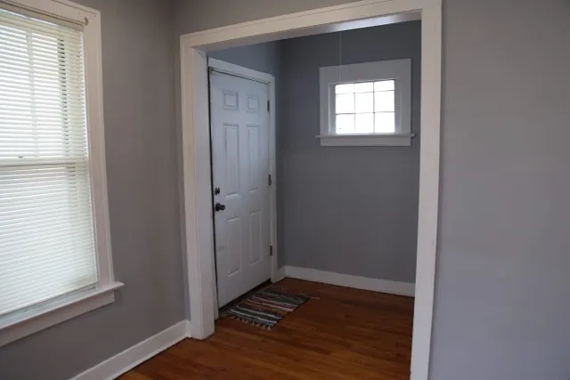 an empty room with wooden floor closet and windows