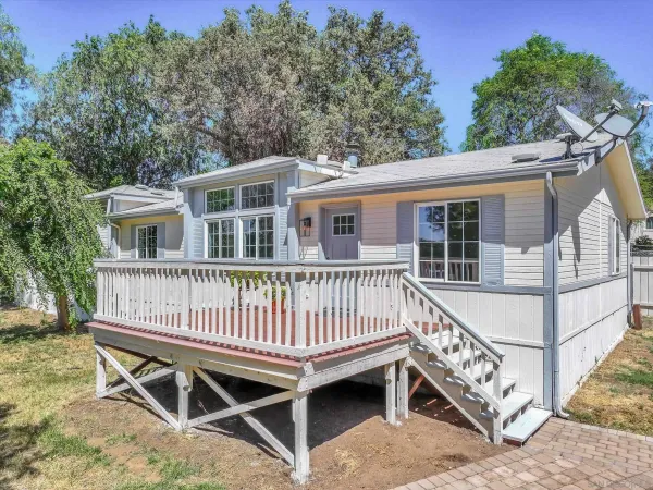 a view of a house with a wooden deck and a trees