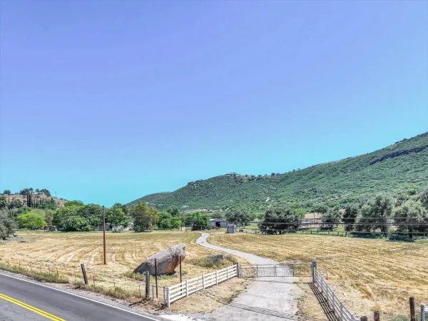 a view of a road with yard and mountain view in back