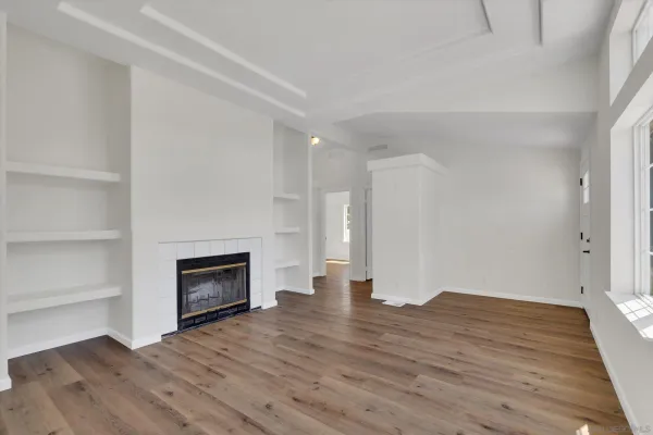 a view of empty room with wooden floor and fireplace